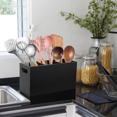 kitchen utensils are in a black container on the counter