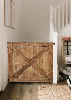 a wooden gate sitting on top of a hard wood floor next to a stair case