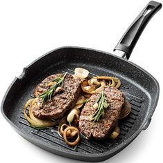 an iron skillet with steaks and onions on it