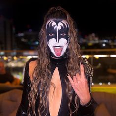 a woman wearing a black and white face paint with her tongue out in front of the camera