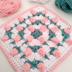 a crocheted square with balls of yarn next to it