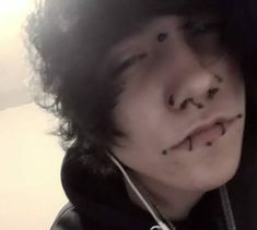 a young man with black hair and piercings on his nose wearing a hoodie