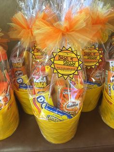 some yellow buckets filled with candy and orange ribbon wrapped in cellophane on top of a shelf