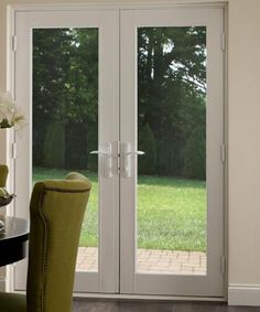 a dining room with french doors leading to a large grassy field in the backround