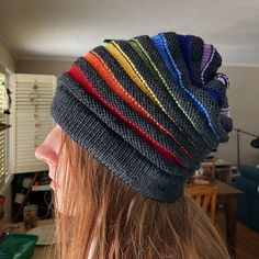 a woman with long hair wearing a multicolored knitted beanie in her living room