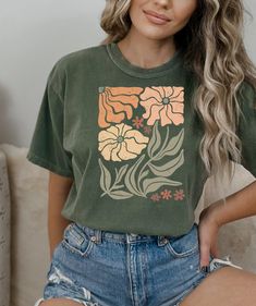 Looking for a comfortable and stylish t-shirt that shows off your love for flowers and nature? Our floral t-shirt with a beautiful wildflowers aesthetic print is the perfect choice! Featuring a stunning print of wildflowers in a gorgeous, natural setting, this t-shirt is perfect for anyone who loves spending time outdoors and appreciates the beauty of nature. The colors are vibrant and eye-catching, and the print is sure to attract compliments wherever you go. Made from high-quality materials, t Casual Green Tops With Plant Print, Green Graphic Tee With Plant Print, Green Graphic Tee With Plants Print, Green Short Sleeve Tops With Plant Print, Trendy Green Floral Print Top, Trendy Green Floral Print Shirt, Green Tops With Plant Print Short Sleeves, Spring Shirt With Front Print In Relaxed Fit, Spring Shirt With Front Print And Relaxed Fit