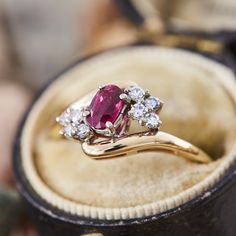 This lovely by-pass style ring is centered with one (1) oval mixed cut natural ruby set into a four-prong head. The ruby is bordered to each side by four (4), prong set, round single cut diamonds. The ring measures 9.5mm at the top, rises 5.5mm above the finger, tapering to 1.2mm wide and 1.2mm thick at the base of the shank. This ring is currently a size 5. Ruby Pearl Diamond Ring, Oval Ruby Jewelry With Brilliant Cut For Weddings, Classic Ruby Cluster Ring With Gemstone, Oval Ruby Diamond Ring With Prong Setting, Oval Brilliant Cut Ruby Ring In 14k Gold, 14k Gold Ruby Ring With Brilliant Cut Oval Shape, Red Oval Cluster Ring With Rose Cut Diamonds, Oval Rose Cut Diamond Ring With Ruby Accents, Oval Ruby Cluster Ring With Rose Cut Diamonds