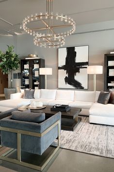 a living room filled with furniture and a chandelier hanging above the couches