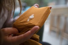 a person holding a piece of cloth in their hand with a tiny white flower on it