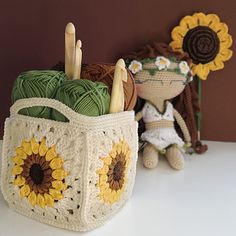 a crochet bag with sunflowers and yarn in it sitting next to a stuffed animal