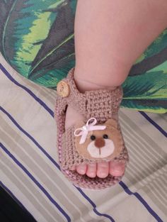 a child's feet wearing crocheted slippers with a bear on them