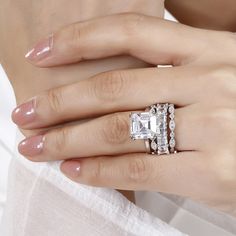 a woman's hand wearing an engagement ring and diamond band