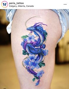 a woman's thigh with blue flowers and a dragon tattoo on the side of her leg