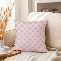 a pink pillow sitting on top of a couch next to a cup and saucer