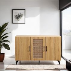 a wooden cabinet sitting next to a potted plant in front of a large window