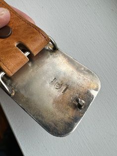 a person holding onto a metal object with a brown leather belt around it's edges