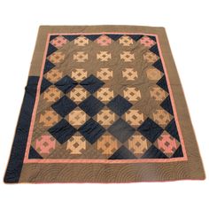 an old quilt is laying on top of a white surface with pink and blue squares