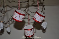 three red and white cups hanging from a chandelier with twine of string