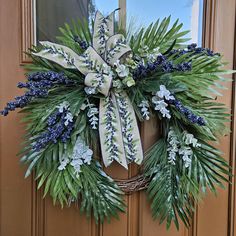 a wreath with blue flowers and greenery hangs on the front door's wooden door