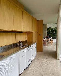 an empty kitchen with wood cabinets and white appliances in front of a sliding glass door