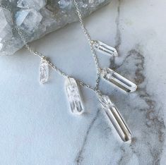 This multi stone quartz necklace features 5 crystals that have been wire wrapped by hand and dangle from a sparkling chain in the metal of your choice. The middle stone is chunky, while the two stones on each side will be gradually smaller. Necklace is 15 inches in length with additional 3 inches of extender chain making an adjustable clasp and a length of up to 18 inches.~Reasons to love crystal quartz~Clear quartz amplifies energy and is useful for healing, manifesting, and meditation. It also Clear Crystal Gemstone Necklaces, Clear Crystal Necklaces With Gemstone, Healing Crystal Necklace With Stones, Wire Wrapped Crystal Necklaces For Healing, Raw Quartz Necklace, Amethyst Bangle, Quartz Choker, Black Leather Choker, Raw Quartz Crystal