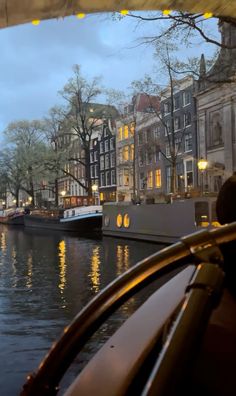 boats are parked on the water in front of some buildings and trees with lights strung from them