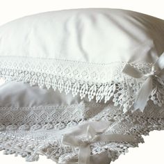 a white pillow with lace on it and a satin ribbon tied around the edge,