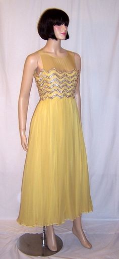 This is an exquisite Elinor Simmons for Malcolm Starr yellow beaded chiffon gown. Malcolm Starr gowns had always been carried in only upscale boutiques and department stores and this one had been purchased at Patricia Feeneys in Ridgewood, New Jersey sometime in the early 1960s. The gown is simple in design and impeccably and masterfully designed and constructed. The bodice is elaborately decorated with beads and sequins and has a back zipper for closure. It is equivalent to a modern day Siz... Yellow Sleeveless Gown For Prom Season, Yellow Evening Dress For Prom Season, Yellow Prom Season Party Gown, Yellow Sleeveless Evening Dress For Wedding, Gold Embellished Georgette Gown, Yellow Chiffon Prom Dress, Yellow Evening Dress For Wedding And Prom Season, Yellow Sleeveless Wedding Gown, Yellow Sleeveless Gown With Fitted Bodice