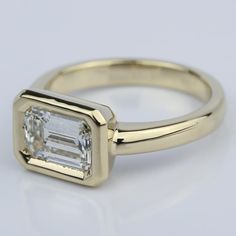 an engagement ring with a baguette cut diamond set in the center, on a white background