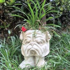 a statue of a dog with a red flower in it's mouth sitting in the grass