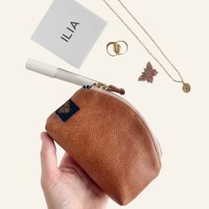 a hand holding a small purse with jewelry on it and a tag attached to the bag