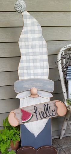 a wooden sign that says hello with a gnome holding a watermelon on it