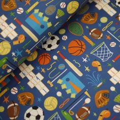 a blue sports themed fabric with basketballs, soccer balls and other items on it