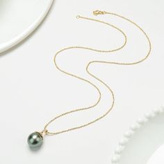 Showcase refined elegance with our sophisticated Long Gold Bead Necklace, featuring a large 14-15mm water-drop shaped Tahitian pearl pendant. This stunning pearl boasts a smooth surface and a deep black color, enhanced by a brilliant luster. The pendant is elegantly set in 18K gold and encrusted with multiple small cubic zirconia stones that wrap around the upper layer of the pearl, adding a luxurious touch. The necklace is crafted from gold-plated copper and measures 45cm in length, making it v Elegant Tahitian Pearl Drop Necklace, Luxury Tahitian Pearl Round Pendant Necklace, Luxury Pearl Necklace With Teardrop Pendant, Elegant Teardrop Pearl Necklace With High Luster, Elegant Teardrop High Luster Pearl Necklace, Luxury Pearl Teardrop Pendant Necklace, Luxury Teardrop Pearl Pendant Necklace, Luxury Tahitian Pearl Pendant Necklace, Tahitian Pearl Necklace With Round Pendant