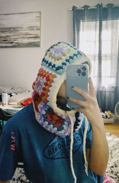 a person wearing a crocheted hat and holding a cell phone up to their face