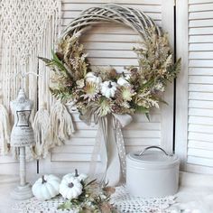 a wreath and some white pumpkins on a table