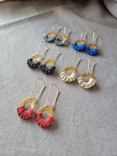 six pairs of earrings are sitting on a table top, each with different colors and shapes