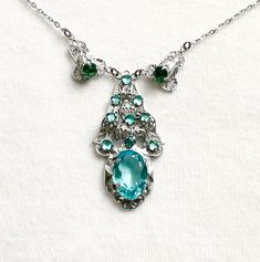 "A lovely vintage turquoise crystal necklace in good vintage condition. The facet cut stones are openback and claw set and very sparkly. The main pendant drop is 1-3/4\" long, the large stone is 1/2\" long and 3/8\" across. The pendant also has 9 small vauxhall/mirror glass stones. The silver metal is very good. The length is 16-1/2\" add another 1-3/4\" to include the total pendant drop. The spring clasp works well. I am happy to combine items to save on postage.  Postage is tracked." Vintage Crystal Pendant Necklaces, Victorian Turquoise Necklace For Wedding, Vintage Green Jeweled Necklace, Vintage Green Jeweled Necklaces, Vintage Green Crystal Jewelry, Vintage Crystal Necklace For Gifts, Vintage Emerald Necklace Gift, Vintage Emerald Necklace For Gift, Vintage Emerald Necklace As A Gift