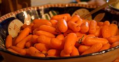 a bowl filled with baby carrots on top of a table