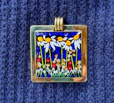 a square glass tile with daisies and ladybugs in it on a blue surface