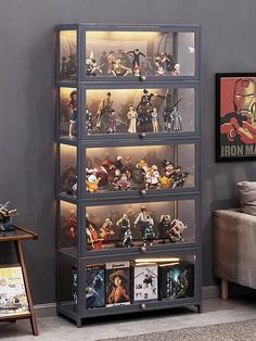 a display case filled with lots of action figures on top of shelves next to a couch