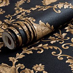 a black and gold wallpaper with an ornate design on it's side, next to a roll of tape