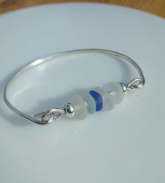 Sea Glass Bangle - Sterling Silver, Seaham Sea Glass, Blue Accent Sea Glass Effect Frosted Bead.  The width of the D shape silver section of the bangle is 2mm.  The size of the bangle width is 7cm approx and would suit a medium to large wrist. Please measure the widest part of your hand or your own bangles to check for size.  The bangle is handmade from sterling silver ( solid 925 silver ). All my silver is sourced from a reputable UK supplier and is made from recycled silver. The beaded section Glass Bangle Jewelry Gift, Glass Bangle Jewelry For Gifts, Handmade Blue Sterling Silver Bangle Bracelet, Silver Beaded Glass Jewelry, Blue Sterling Silver Bangle Bracelet, Silver Glass Jewelry With Silver Beads, Sterling Silver Stackable Beaded Bangle Bracelet, Nickel-free Silver Glass Bracelet, Stackable Sterling Silver Bangle Beaded Bracelets