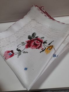 two pieces of white cloth with red and yellow flowers on them, one is folded to the side