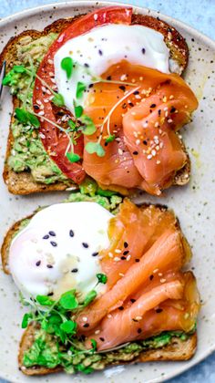 two pieces of toast with salmon, avocado and poached eggs on them