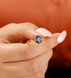 a woman's hand holding a ring with a green stone