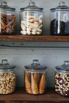 several jars filled with different types of food on top of a wooden shelf next to each other