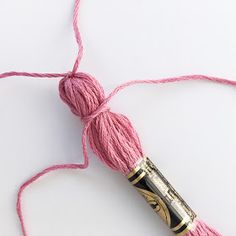 a ball of pink yarn is next to a crochet hook on a white surface