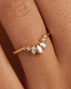 a woman's hand wearing a gold ring with three diamonds on it and the middle finger