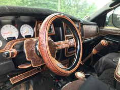 the interior of an old car with wood trim and leather steering wheel cover on it